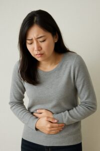 不安そうにお腹を抱える女性の写真