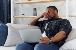 膝にPCを置く男性