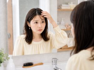 髪の毛の生え際を気にする女性の画像